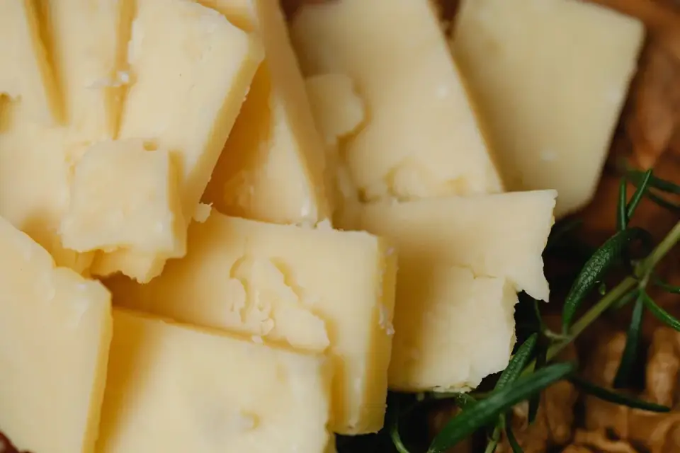 A block of aged cheddar cheese sits on a wooden cutting board next to a small knife