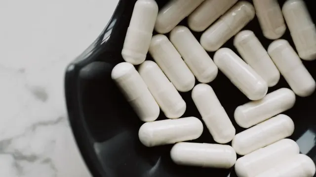 A bottle of children's chewable vitamins spilled next to a dog's bowl of kibble