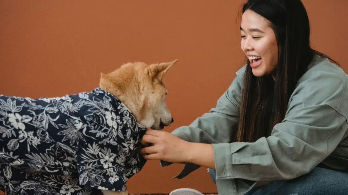 A dog owner kneeling on a kitchen floor next to a whining dog