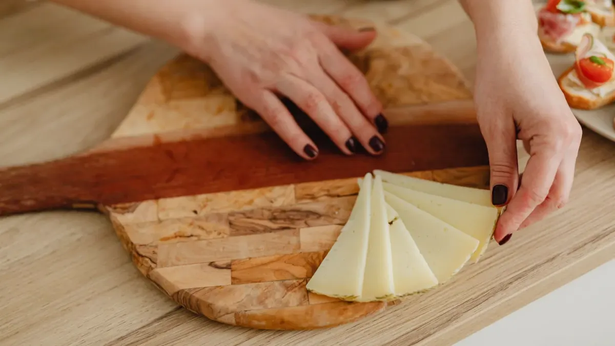 A dog's owner holds out a small cube of cheese in the kitchen
