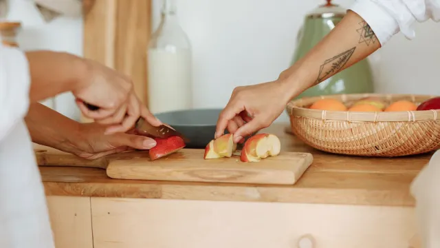 A dog sniffing a plate of sliced apple on a kitchen counter