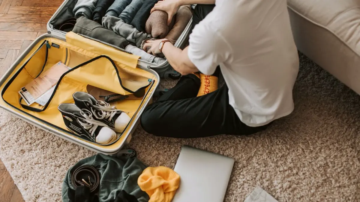 A dog stretched out on a hotel room floor beside an open suitcase