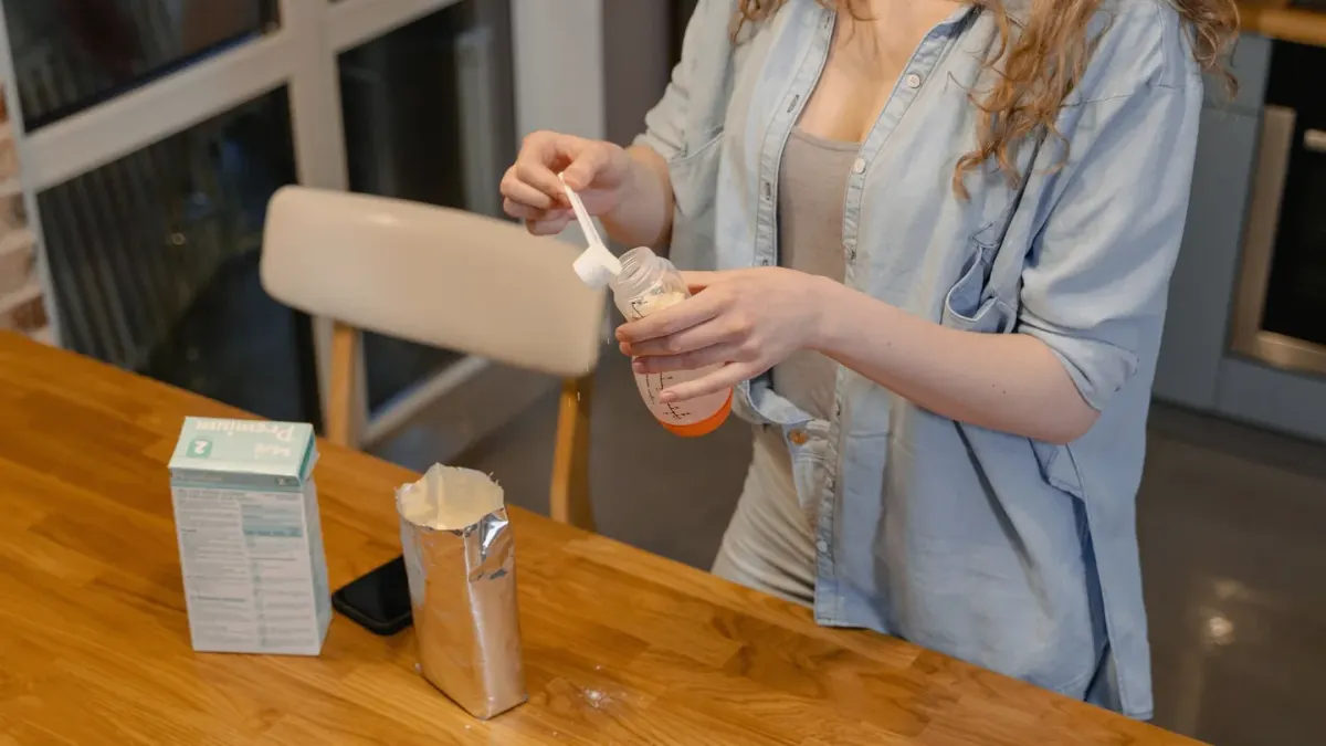 An owner spooning a scoop of powder over a dog's food bowl in a kitchen
