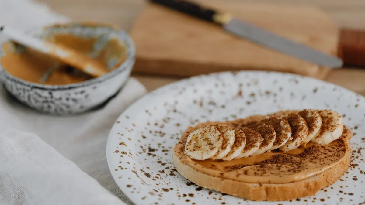 Banana slices arranged on a wooden cutting board beside an empty dog bowl
