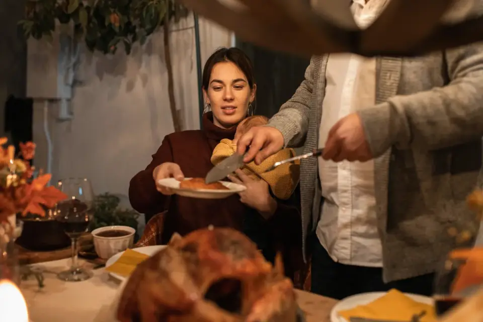 Dog sitting near a holiday dinner table watching turkey being carved