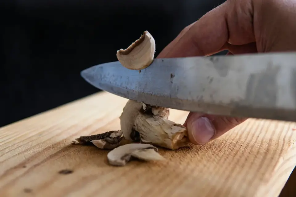 Sliced fresh button mushrooms on a wooden cutting board