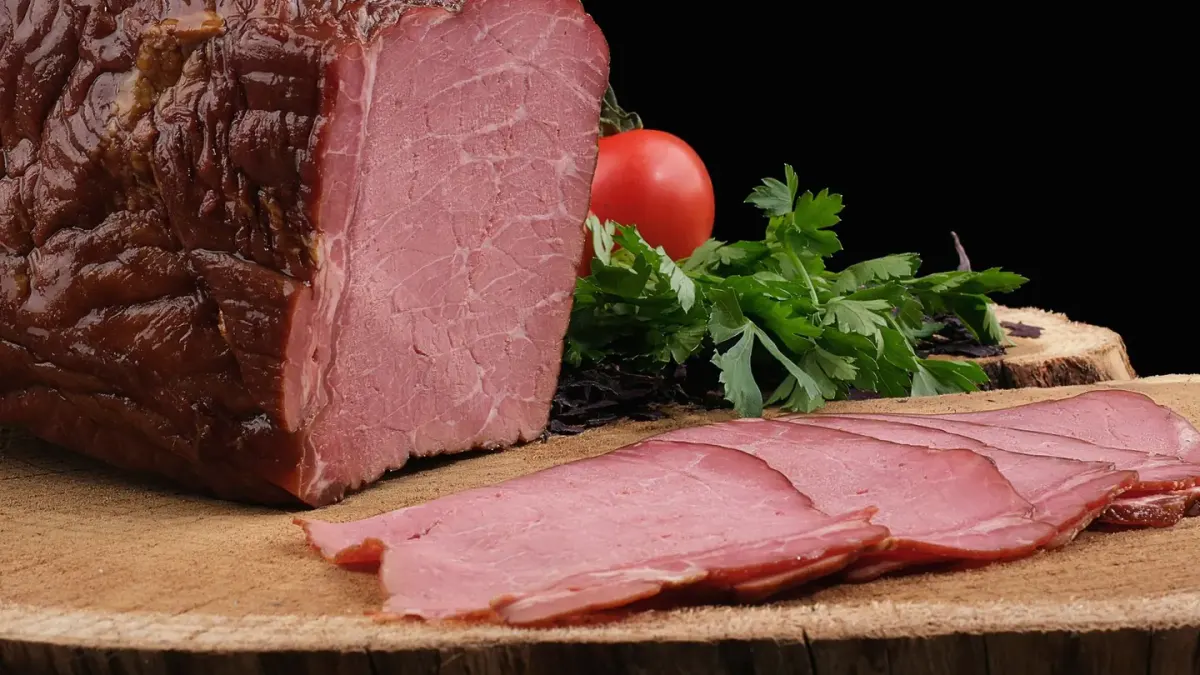 Sliced plain roasted turkey on a cutting board next to a dog waiting nearby